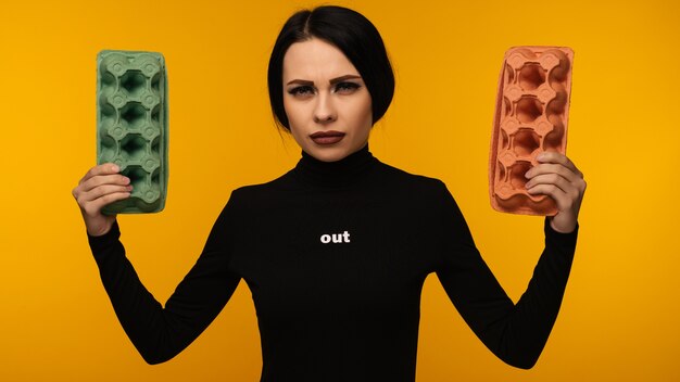 Woman portrait hold cardboard box isolated on yellow background.The concept of environmental pollution by human waste products.