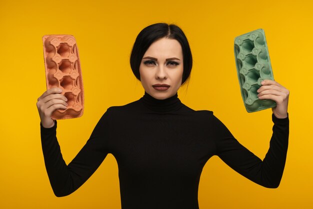 Woman portrait hold cardboard box isolated on yellow.The concept of environmental pollution by human waste products.