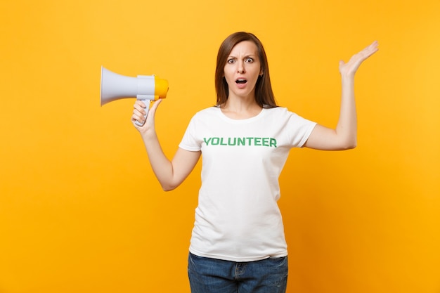 Женский портрет в белой футболке, написанный надписью зеленый заголовок волонтерского крика в громкоговорителе публичного адреса, изолированном на желтом фоне. добровольная бесплатная помощь, концепция работы благотворительной благодати.