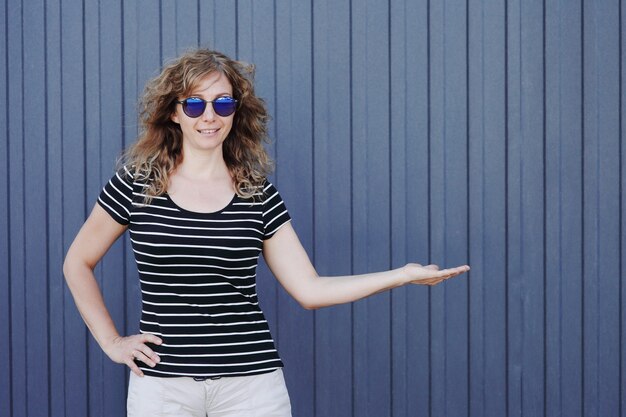 Woman portrait in sunglasses on blue striped wall in the background