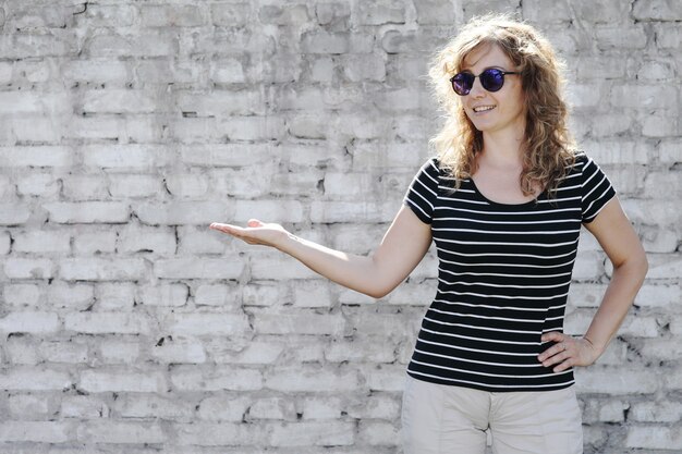 Woman portrait in sunglasses on White brick wall in the background