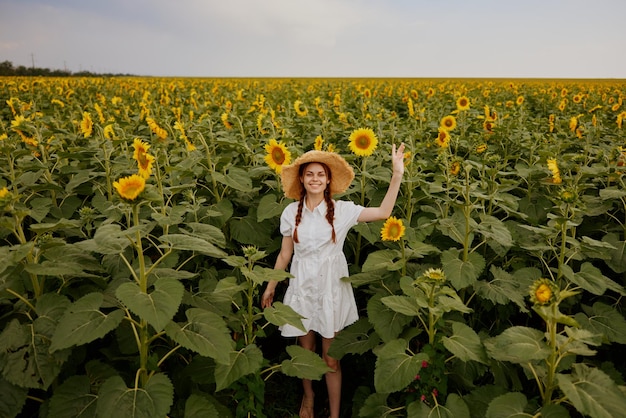 Woman portrait in a white dress walking on a field of sunflowers landscape