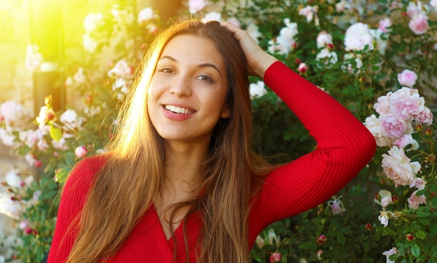 Photo woman posing among blooming roses in spring time