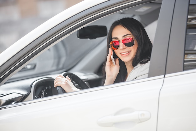 車の中でポーズをとる女性。女性の運転車。自動車の魅力的な若い女性。屋外の女性。