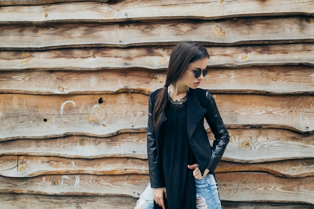 Woman posing near wooden wall