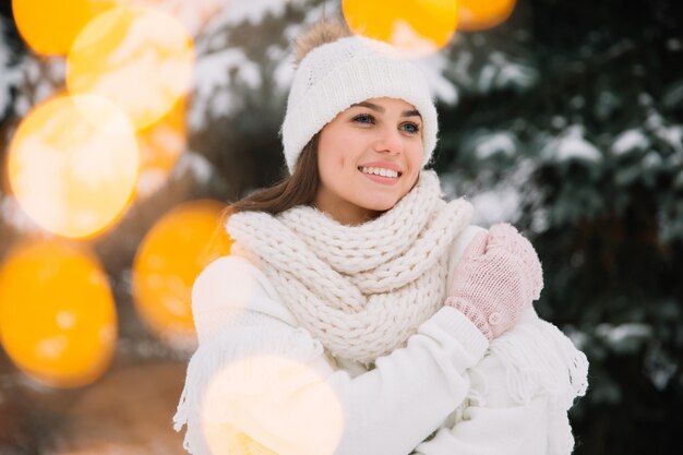 Woman posing in park with Christmas lights. Winter holidays concept.