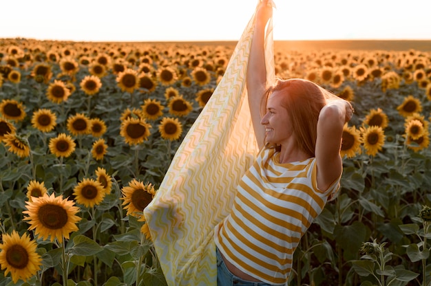 Woman posing in sunflower field at sunset