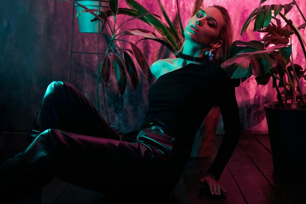 Woman posing with neon light and plants