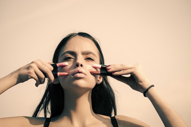 Woman posing with pink lips and lipsticks on white sky