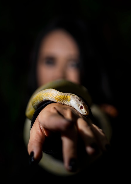 Женщина позирует со змеей на темной стене