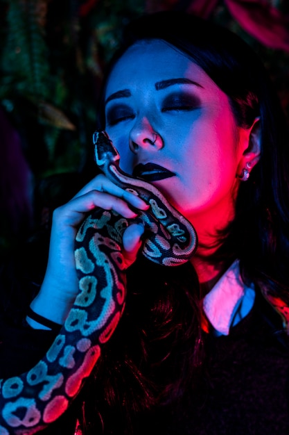 Woman posing with snake on dark wall