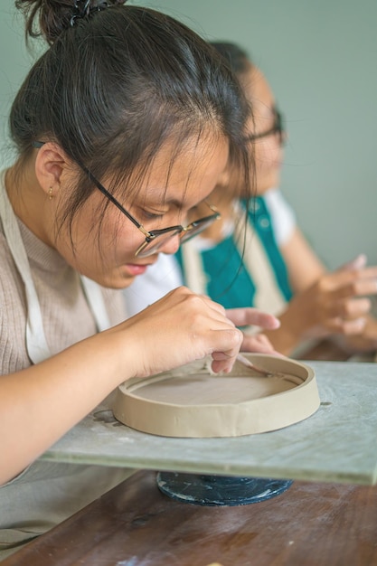 Woman potter working on potters wheel making ceramic pot from
clay in pottery workshop art concept focus hand young woman
attaching clay product part to future ceramic product pottery
workshop