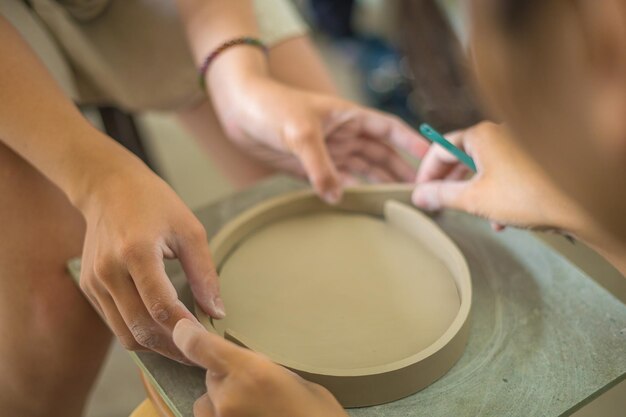 Woman potter working on potters wheel making ceramic pot from
clay in pottery workshop art concept focus hand young woman
attaching clay product part to future ceramic product pottery
workshop