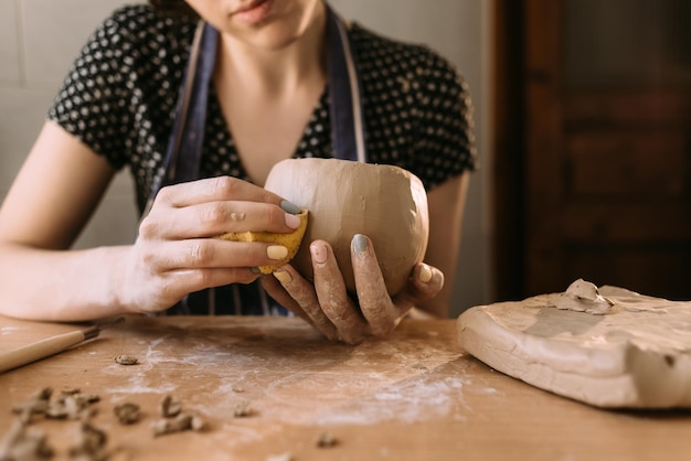 Donna vasaio lavora con l'argilla nel suo laboratorio di casa le mani del maestro primo piano impasta e scolpisce l'argilla prima del lavoro messa a fuoco selettiva hobby creativo