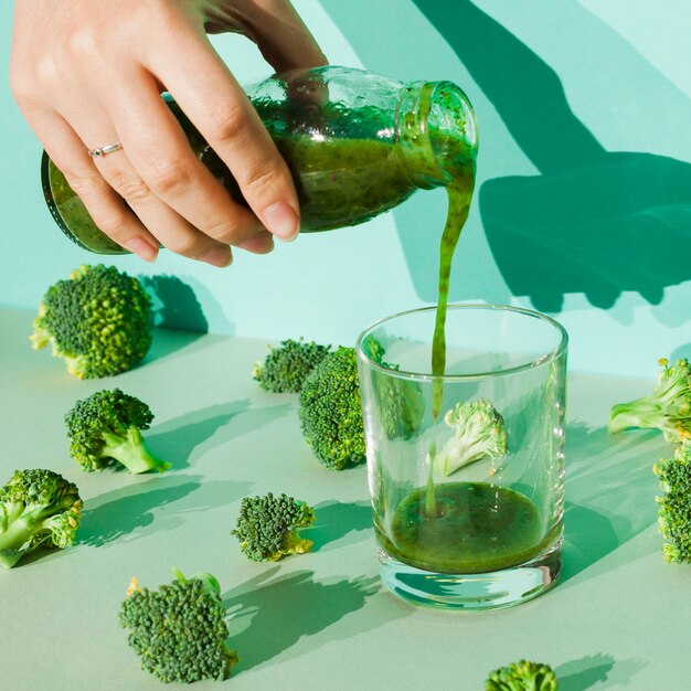 Woman pouring broccoli smoothie into glass