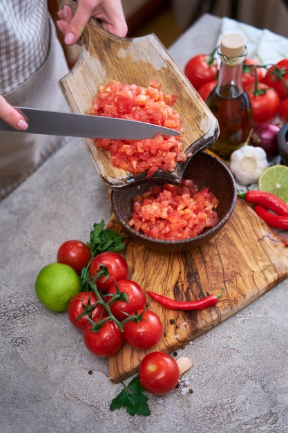 Donna che versa i pomodori sbollentati tritati in una ciotola di legno