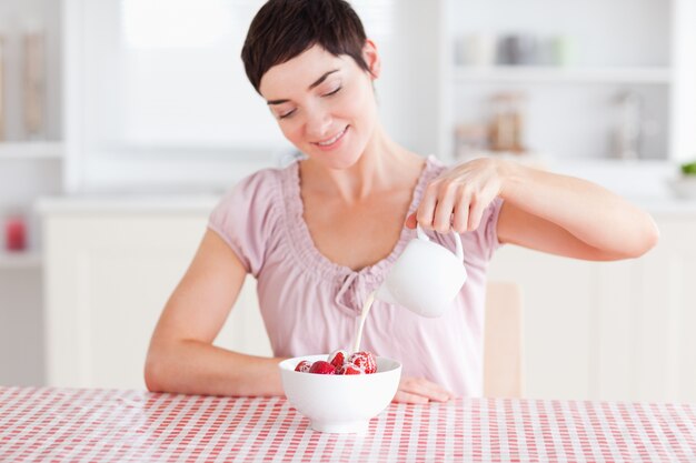 Photo woman pouring cream over strawberries