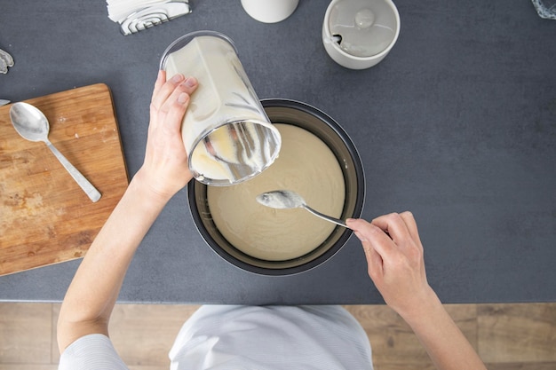 Woman pouring dough into baking dish Top view flat lay