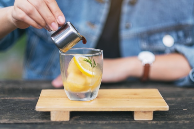 A woman pouring espresso shot into a glass of ice and lemon