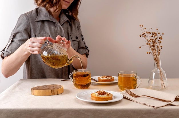 Woman pouring green herbal tea in glass cup Hot tea is in the glass cups