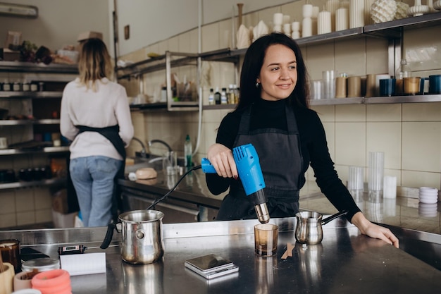 Donna che versa cera fusa in un contenitore di candele ambrate business ecologico e vegano accessori per candele in cera di soia fatto a mano con amore lavoro a distanza negozio online sul posto di lavoro