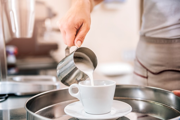 Woman pouring milk in coffee