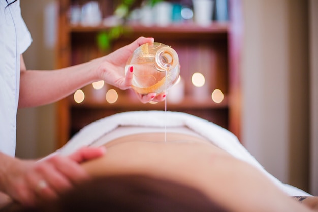 woman pouring oil on client