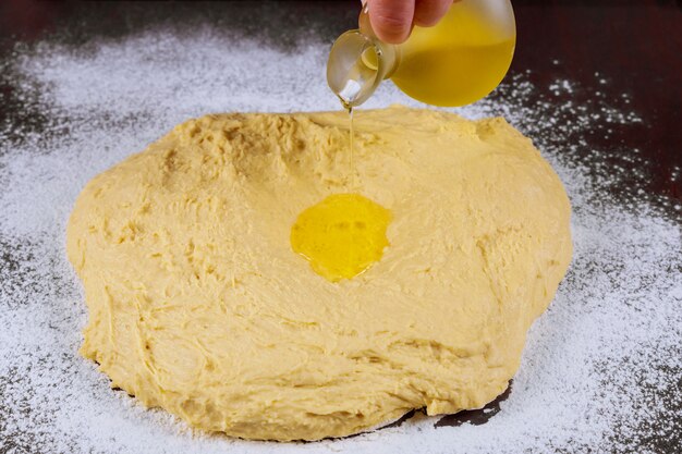 Woman pouring oil on dough for making pasta