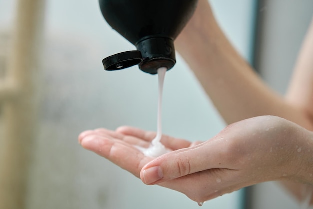 Woman pouring shampoo on hand in bathroom