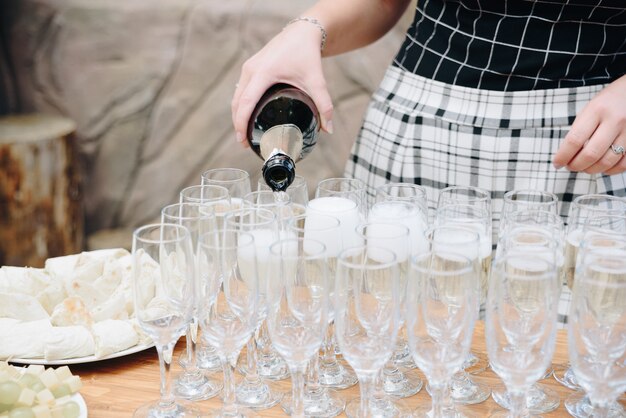Женщина наливает шампанское в бокалы