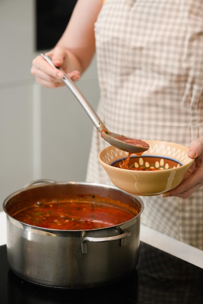 A woman pours freshly prepared Ukrainian borscht onto a plate