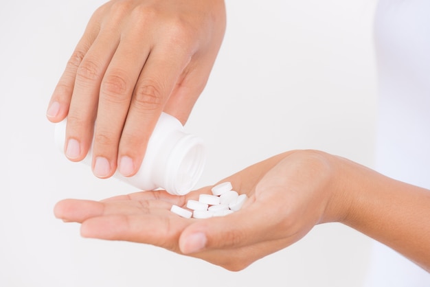 Woman pours out medicine into her hand. Healthcare and medical concept.