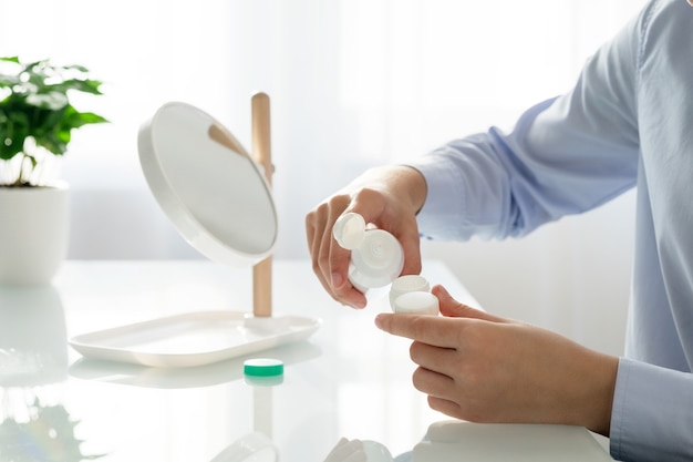 A woman pours a solution into a contact lens container