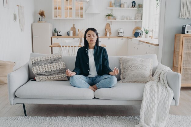 Photo woman practice yoga relax breathing sitting on sofa at home healthy lifestyle stress relief