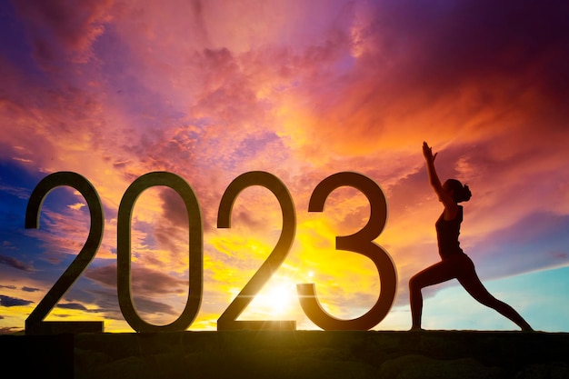 Foto la donna pratica yoga con 2023 numeri all'alba