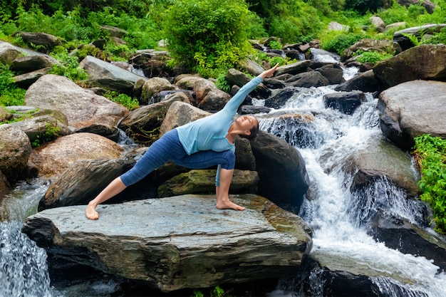 Woman practices yoga asana Utthita Parsvakonasana outdoors