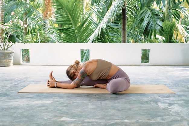 Woman practicing advanced yoga on organic mat series of yoga poses tropical background