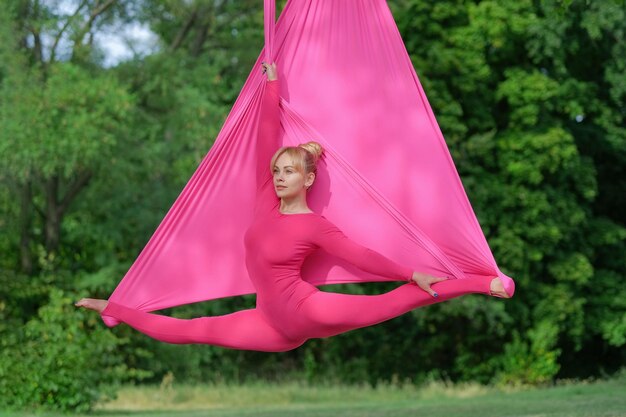 Woman practicing aerial yoga outdoors