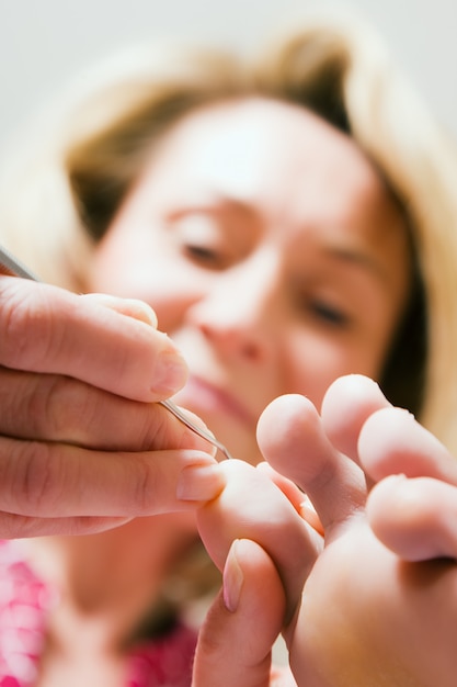 Donna che si esercita in podologia prendendosi cura di un piede; concentrarsi sul viso