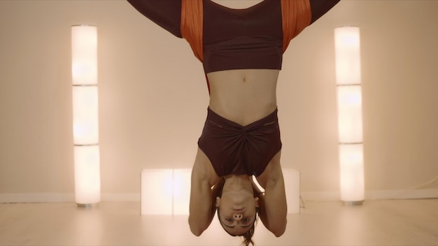 Woman practicing inverted butterfly pose in hammock Lady doing antigravity yoga