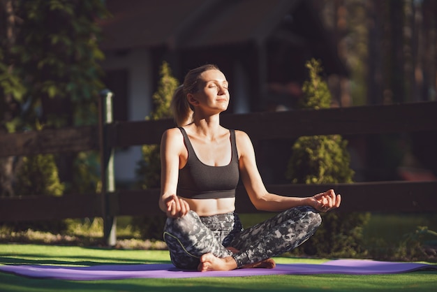 Woman practicing morning yoga at backyard. Healthy lifestyle.