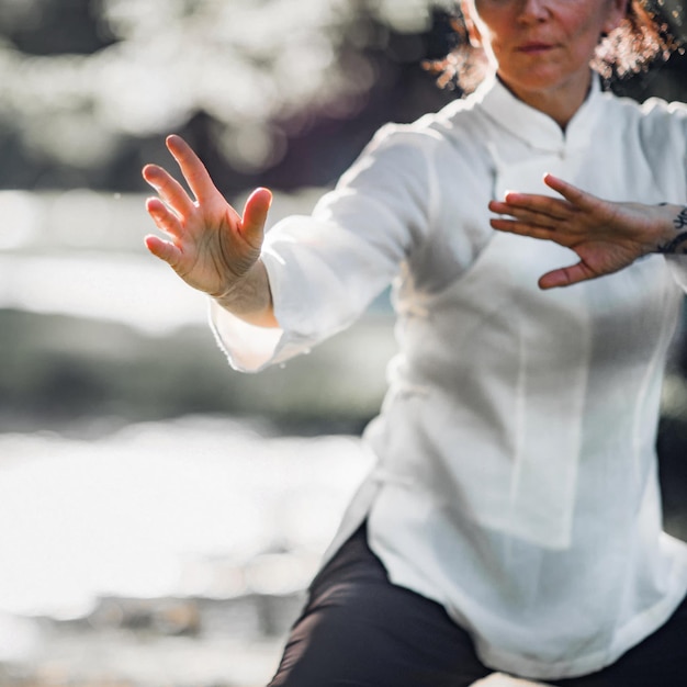 Foto donna che pratica tai chi quan nel parco