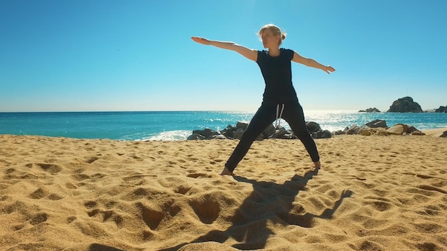海の海岸でヨガのアーサナを練習する女性 柔軟性運動をするフィットガール