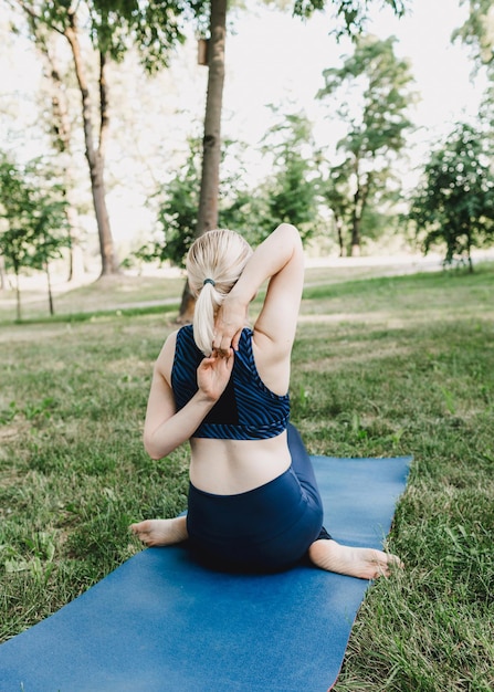 A woman practicing yoga asanas outdoors A young attractive slender fitness girl in a bodysuit relaxe