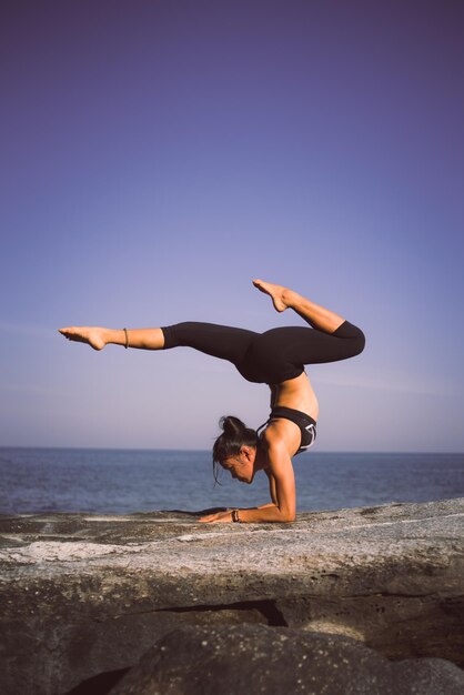 Женщина практикует йогу на пляже на фоне неба