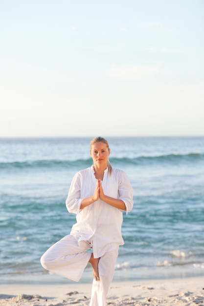 Donna che praticano yoga in spiaggia
