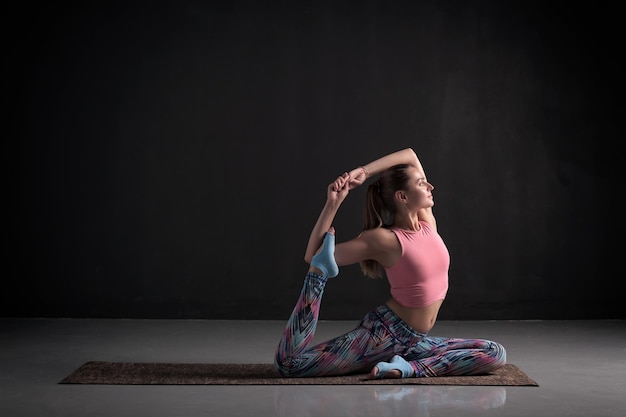 Женщина, практикующая йогу, делает упражнение "Одноногий королевский голубь"
