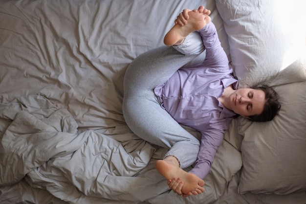 Woman practicing yoga doing Happy Baby Dead Bug Pose Ananda Balasana