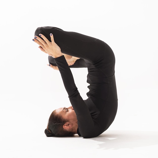 Woman practicing yoga doing Urdhva Padmasana exercise inverted lotus pose side view