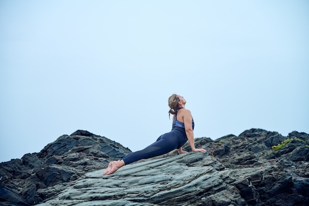 Donna che pratica yoga di fronte al mare